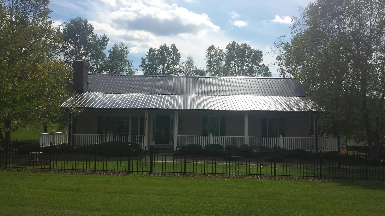 Gray metal roof on a brick ranch with a full width front porch — Gutter Guard Installation work by our crew in Belvidere